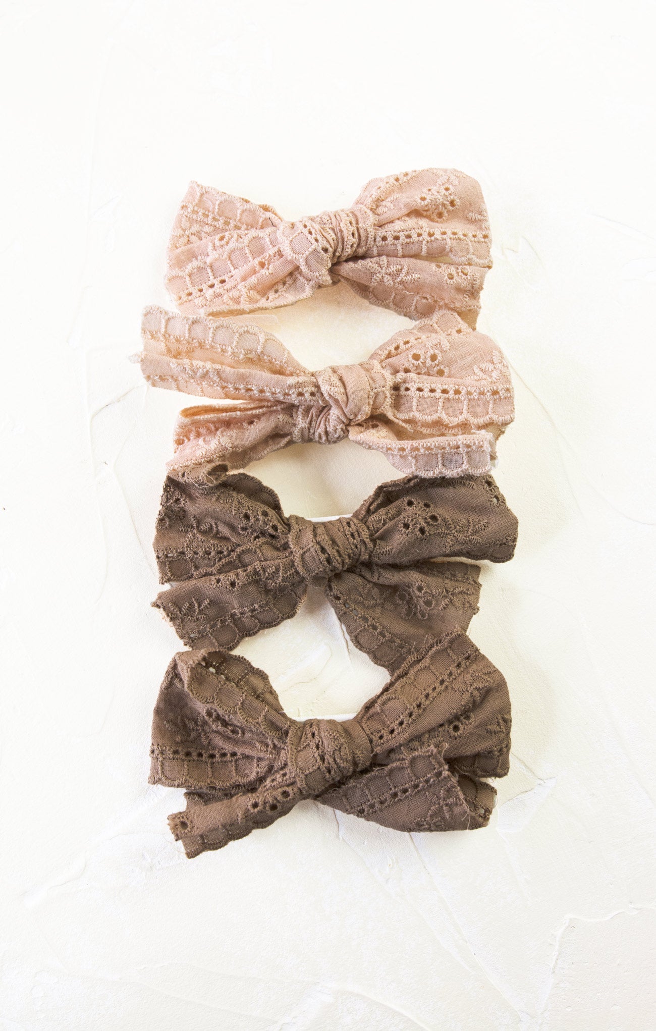 Set of three lace hair bows in pink and brown on a white background