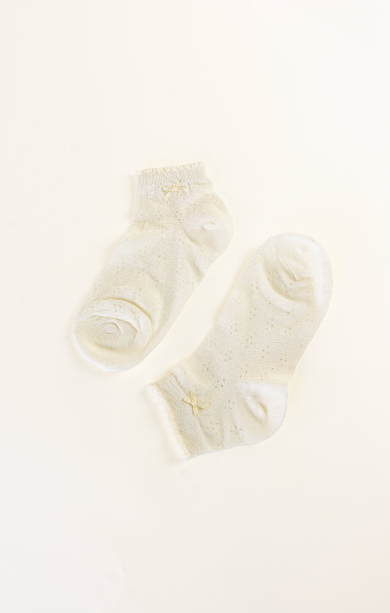 Pair of white socks with a brand logo on a light beige background