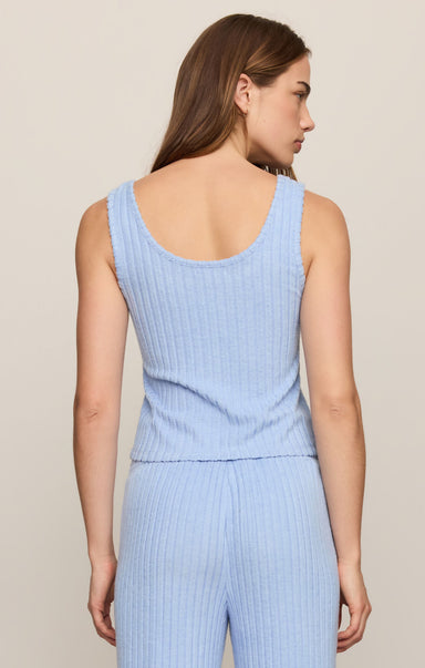 Woman wearing a light blue ribbed jumpsuit against a beige background