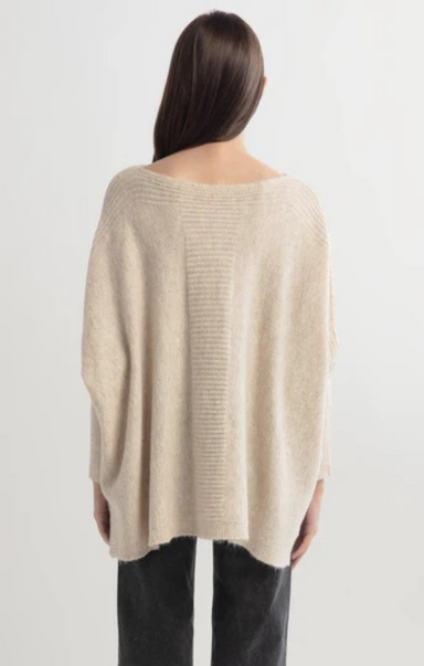 Beige sweater worn by a person on a white background