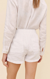 Person wearing a light-colored long-sleeve top and white shorts on a beige background