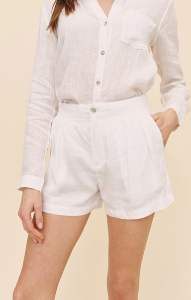 Person wearing a white button-up shirt and white shorts on a beige background