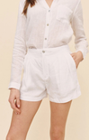 Person wearing a white button-up shirt and white shorts on a beige background