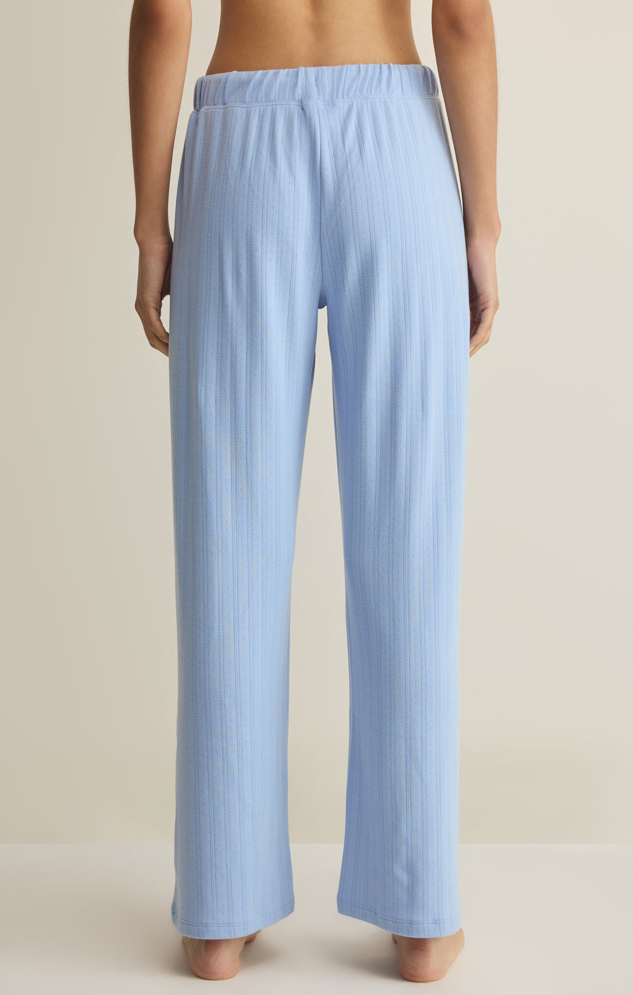 Light blue ribbed lounge pants worn by a person on a beige background