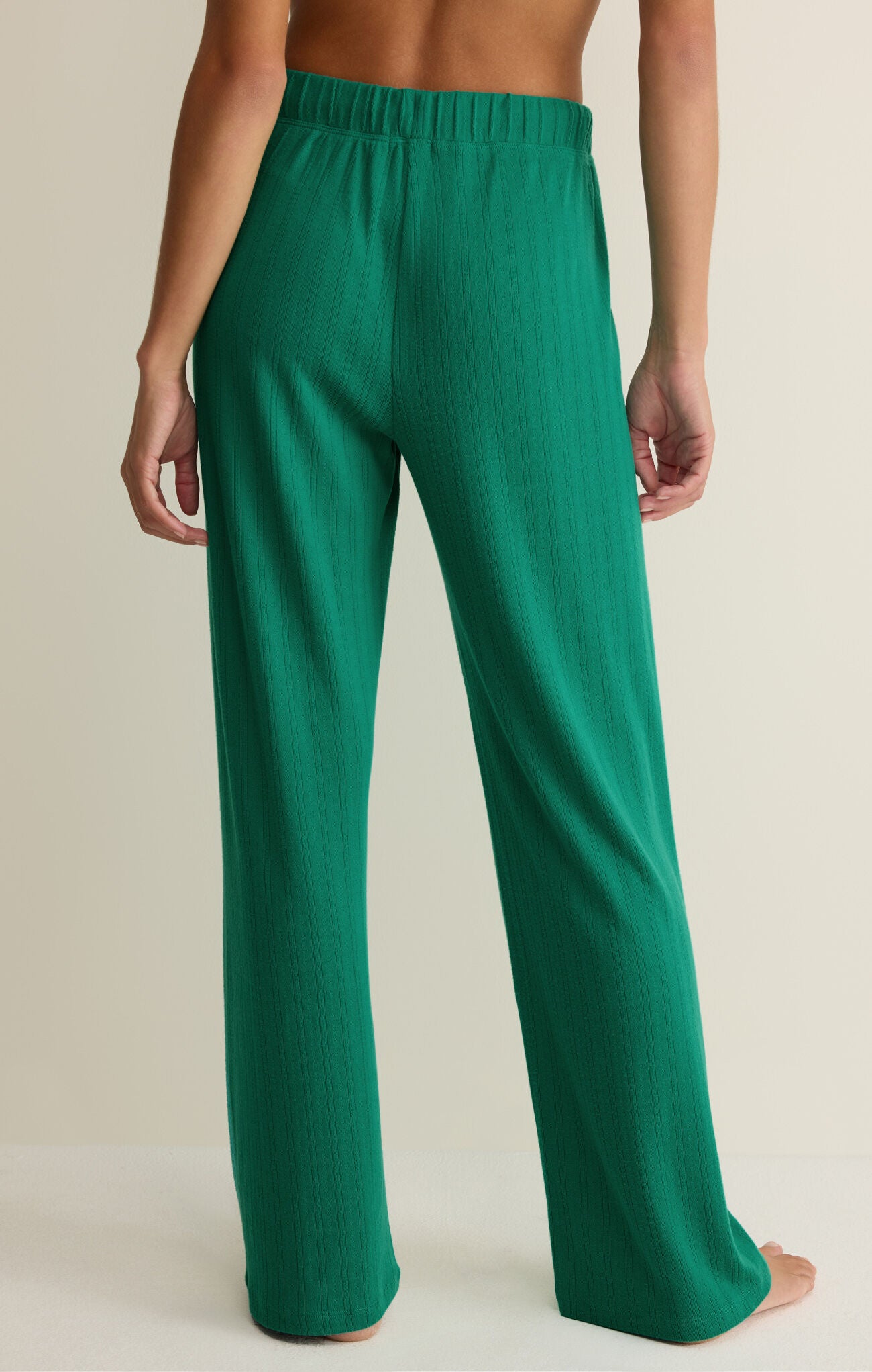 Green pants worn by a person on a beige background