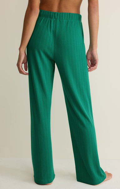 Green pants worn by a person on a beige background
