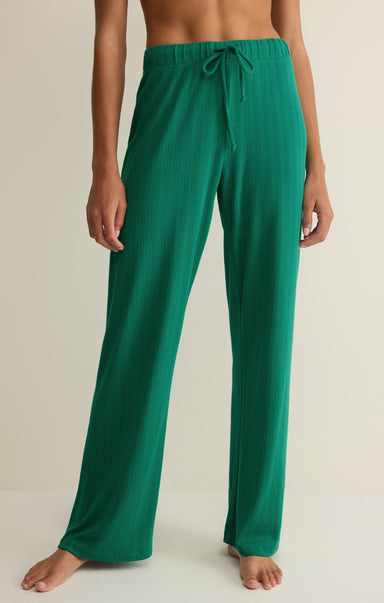 Green pajama pants worn by a person on a beige background