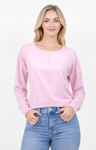 Woman wearing a pink sweater and blue jeans on a white background