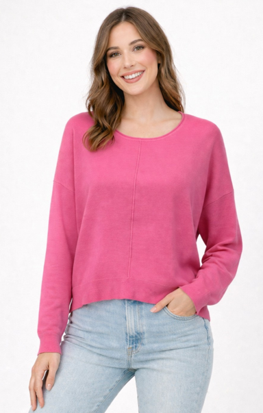 Woman wearing a pink sweater and light blue jeans on a white background