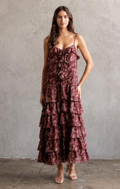 Woman wearing a tiered, floral dress against a gray background