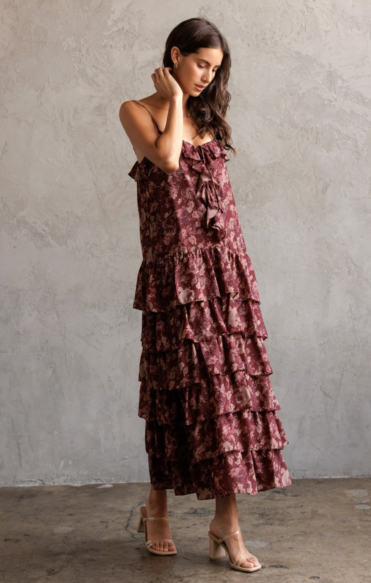 Woman wearing a tiered ruffled dress against a plain wall.