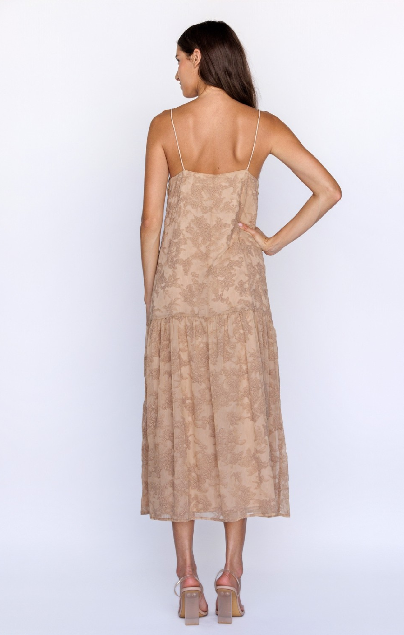Woman wearing a beige dress with thin straps on a white background