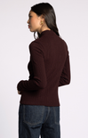 Woman wearing a brown ribbed sweater and blue jeans on a white background
