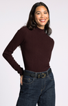 Woman wearing a brown ribbed sweater and blue jeans on a white background