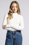 Woman wearing a white sweater and blue jeans against a plain background