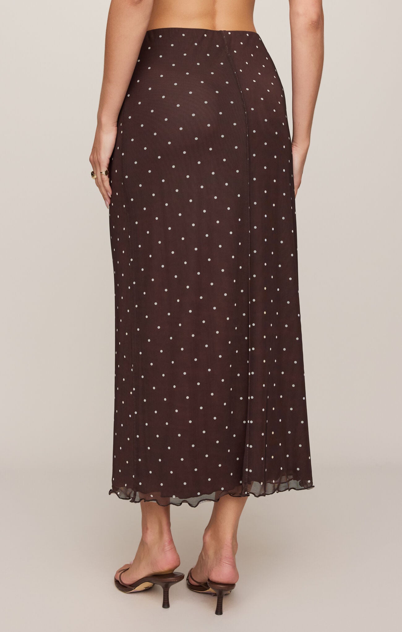 Woman wearing a brown polka dot skirt on a plain background