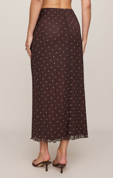 Woman wearing a brown polka dot skirt on a plain background