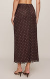 Woman wearing a brown polka dot skirt on a plain background