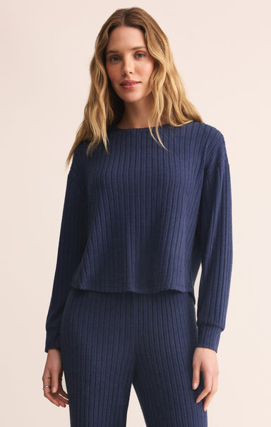 Woman wearing a navy ribbed sweater and pants on a beige background