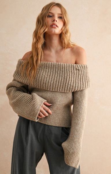 Woman wearing a beige off-shoulder sweater against a beige background
