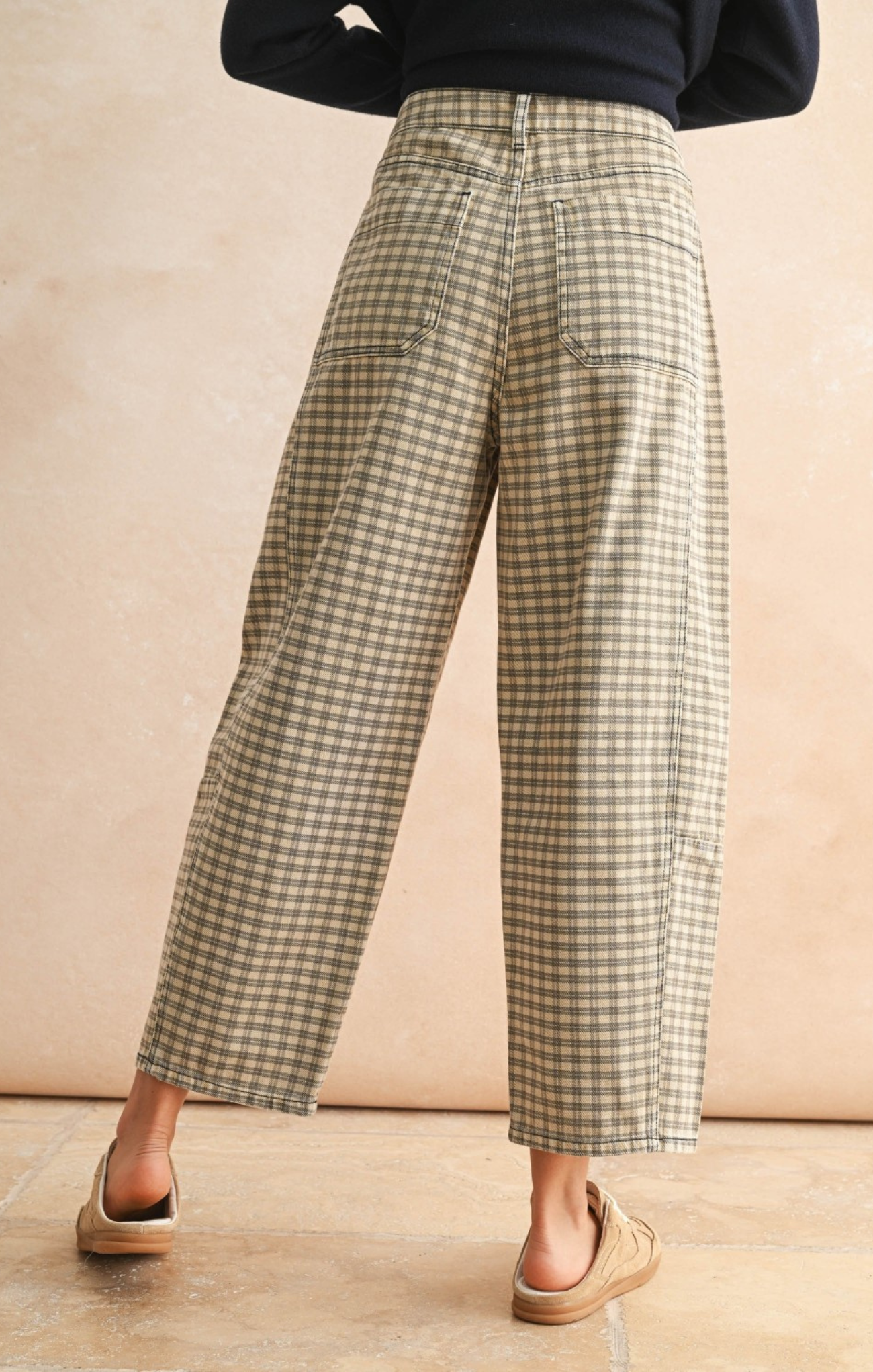 Person wearing plaid pants against a beige background