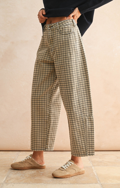 Person wearing plaid pants standing against a beige wall.