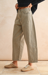 Person wearing plaid pants standing against a beige wall.