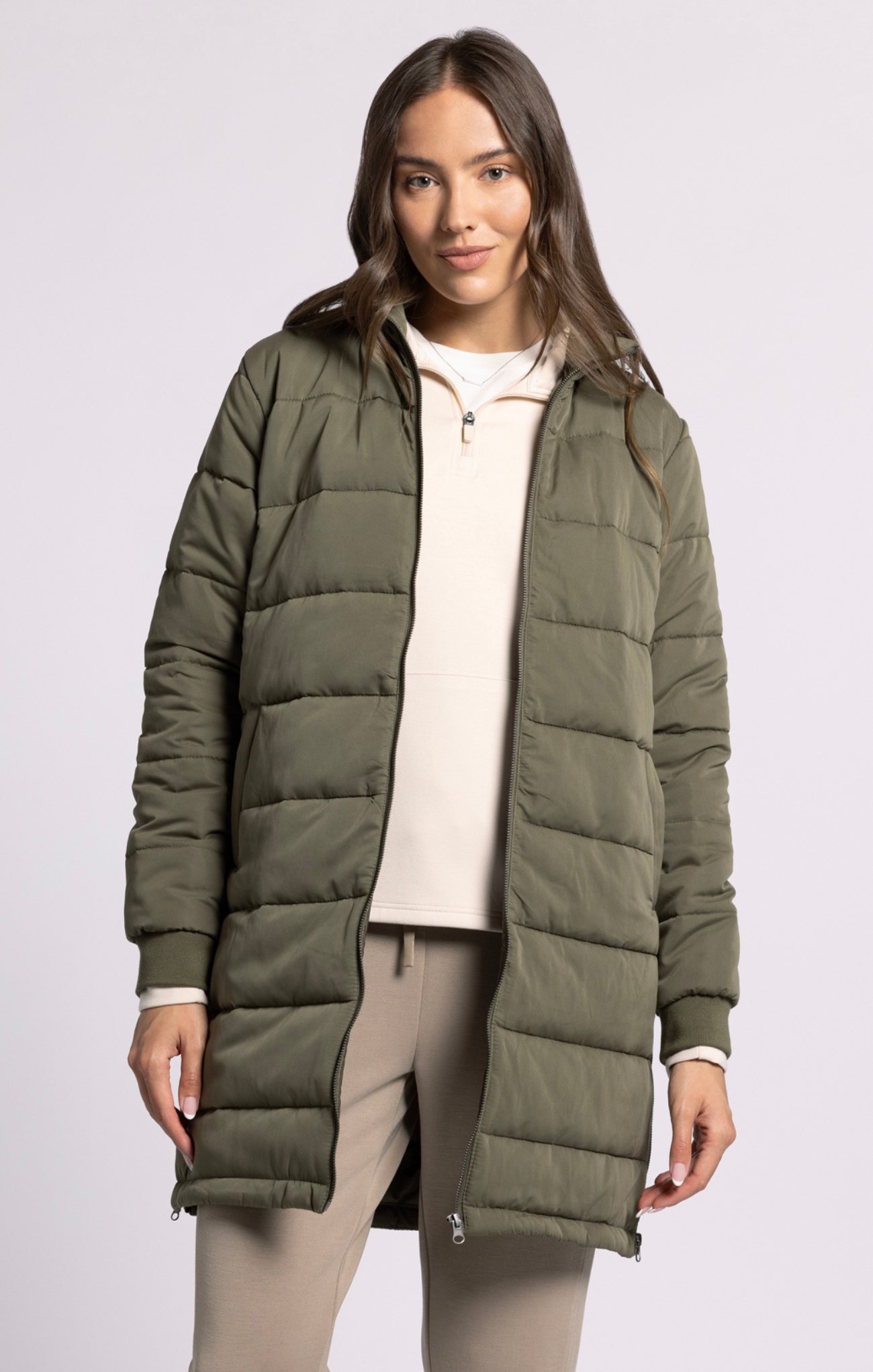 Woman wearing a green puffer jacket on a white background