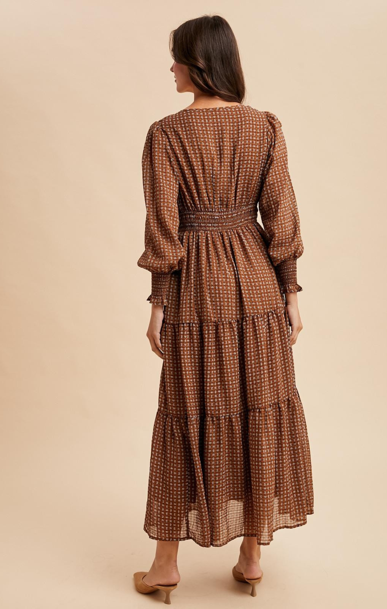 Woman wearing a brown checkered dress on a beige background
