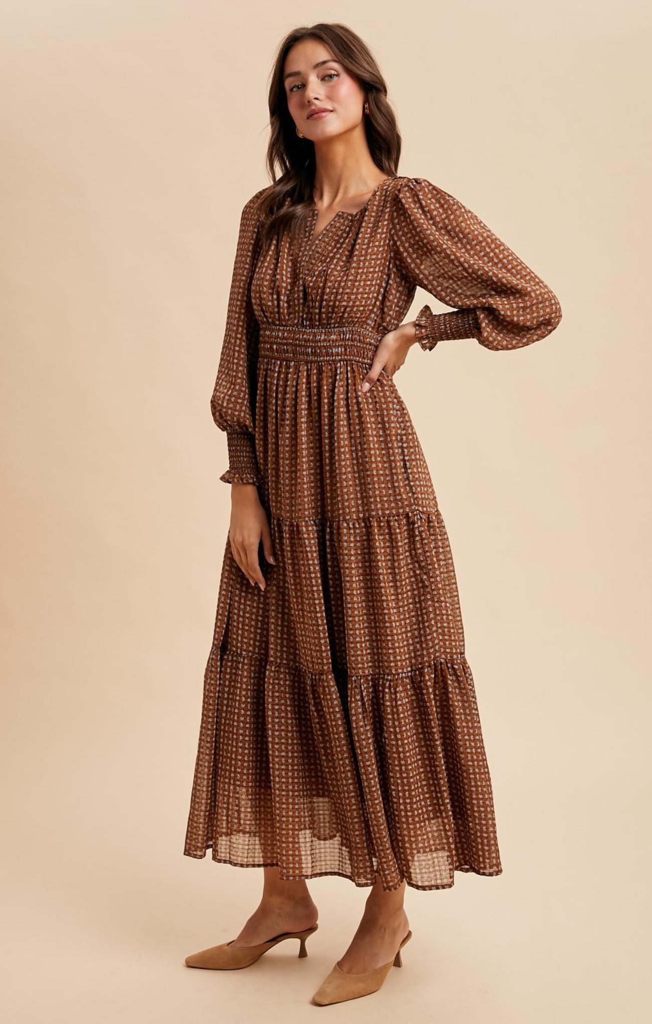 Woman wearing a brown patterned dress against a beige background