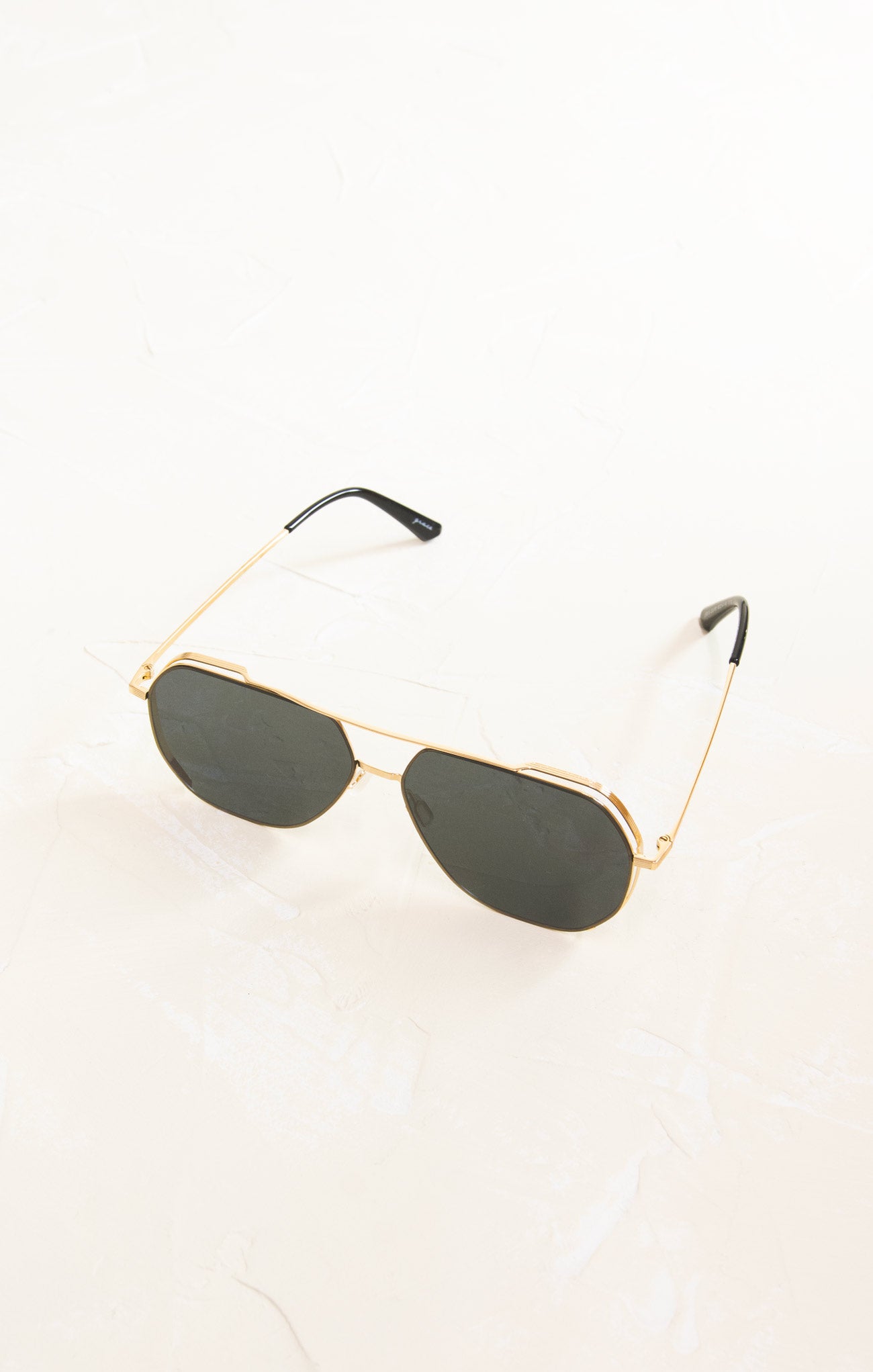 Gold-framed sunglasses with dark lenses on a white background