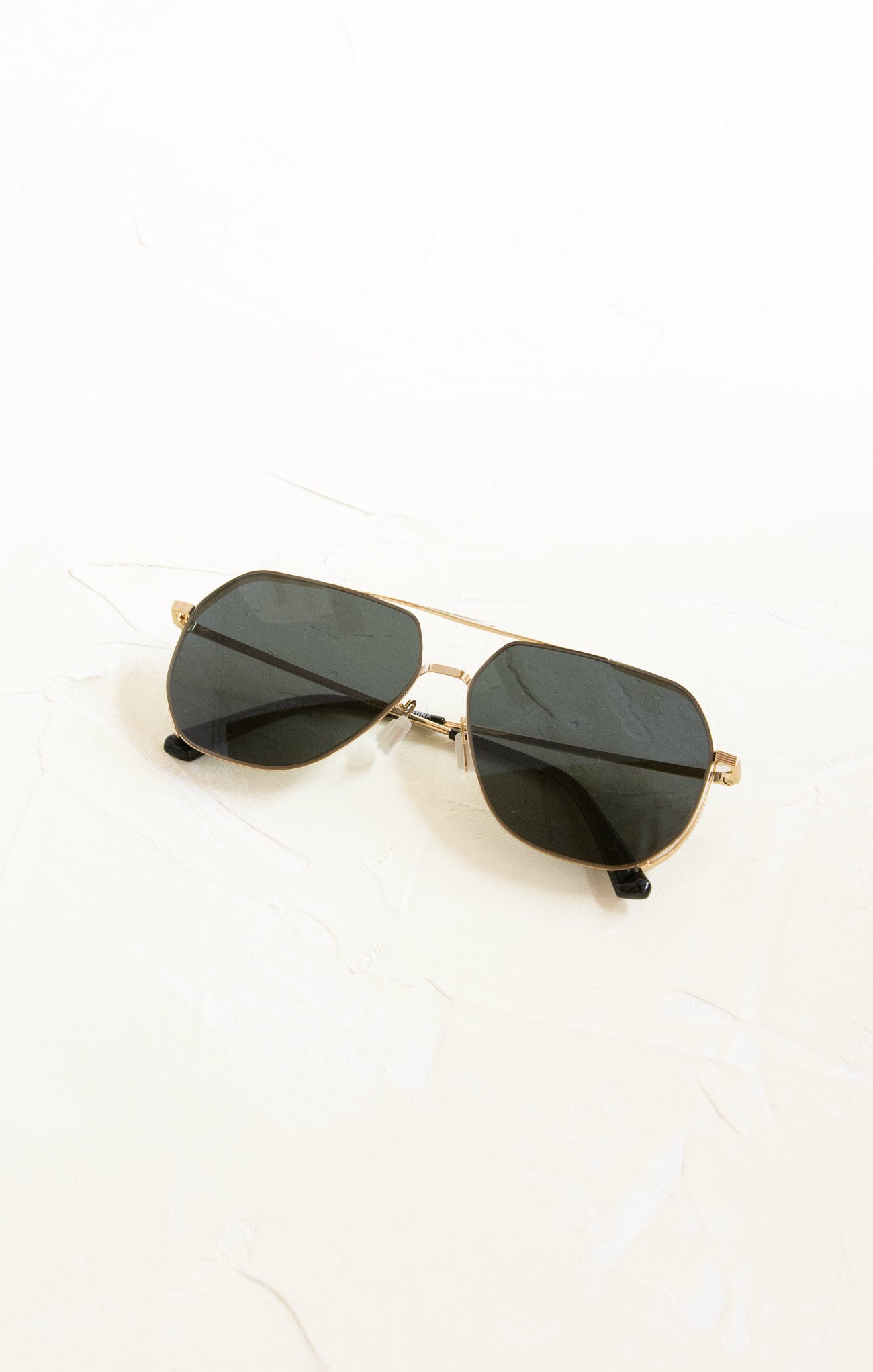 Sunglasses with gold frame and black lenses on a white background