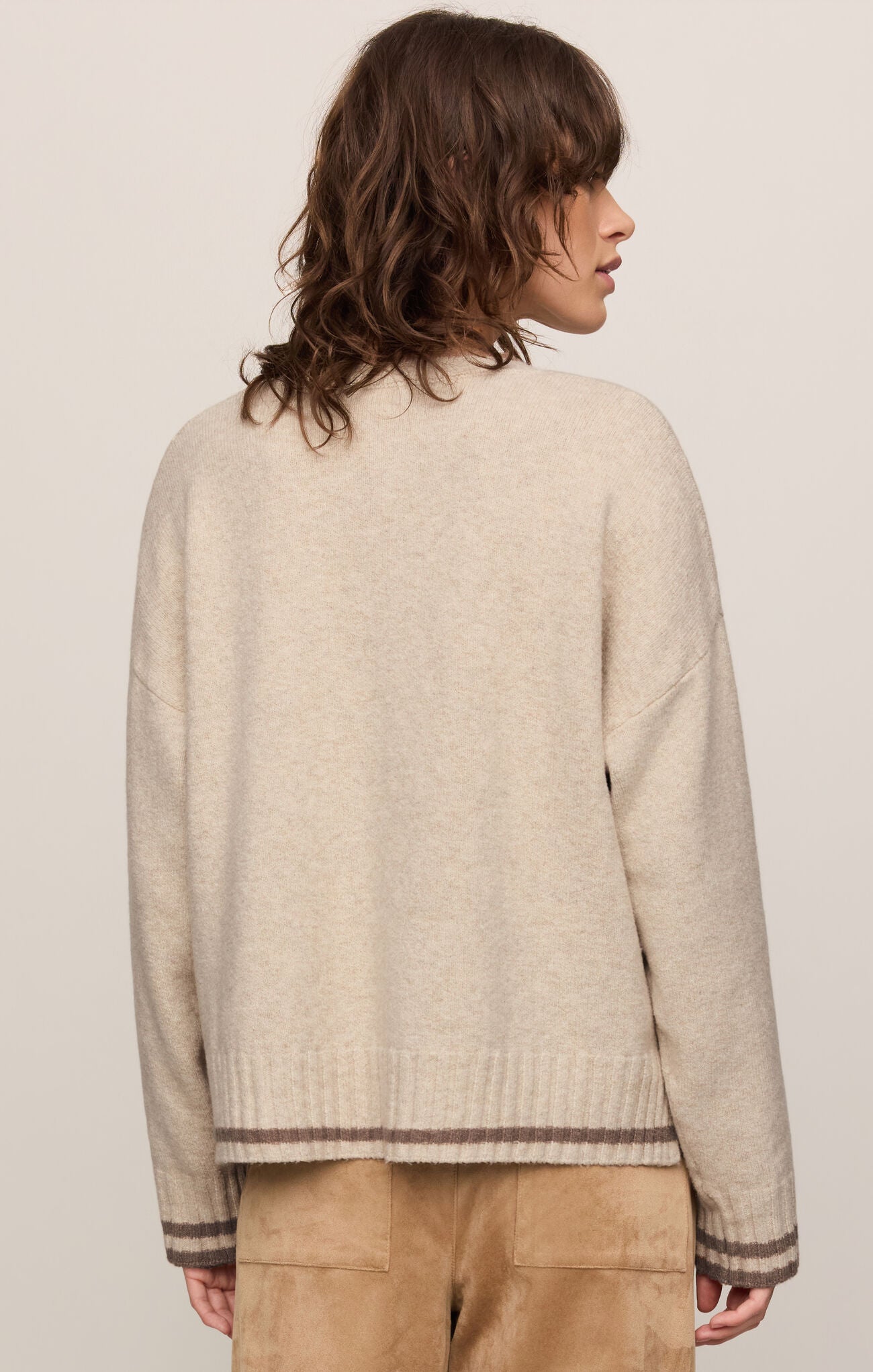Person wearing a beige sweater with a plain background