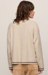 Person wearing a beige sweater with a plain background