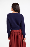 Person wearing a navy sweater and red skirt on a white background