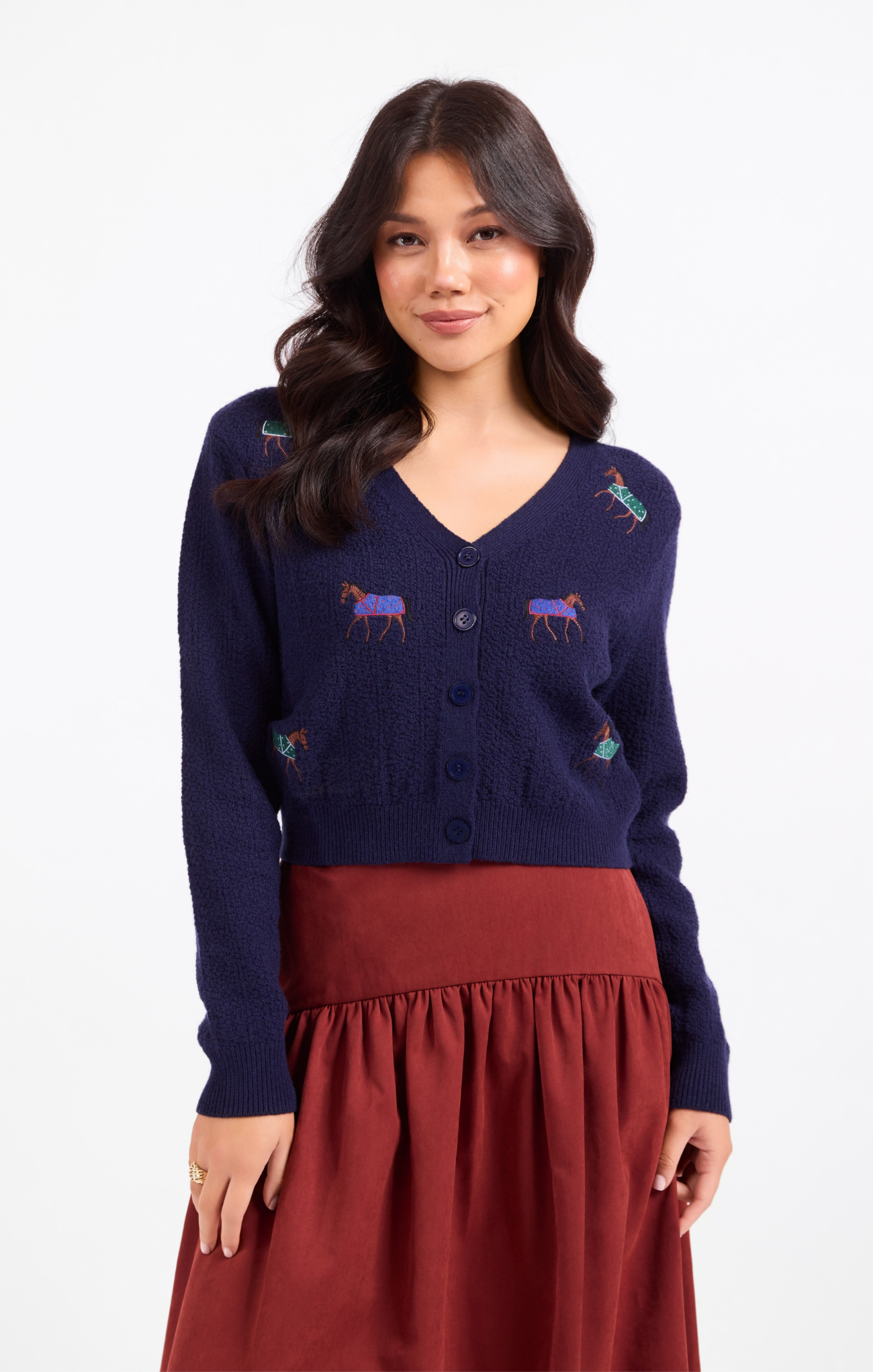 Woman wearing a navy blue cardigan with embroidered designs on a white background