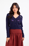 Woman wearing a navy blue cardigan with embroidered designs on a white background