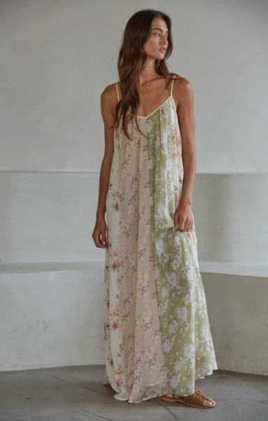 Woman wearing a floral dress standing against a plain wall.