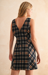 Woman wearing a plaid dress with a beige background