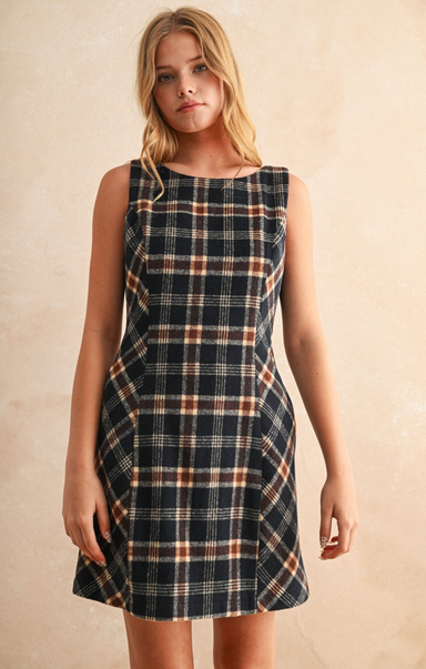 Woman wearing a plaid dress against a beige background