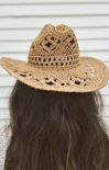 Brown straw hat with wide brim worn by a person with long dark hair against a neutral background