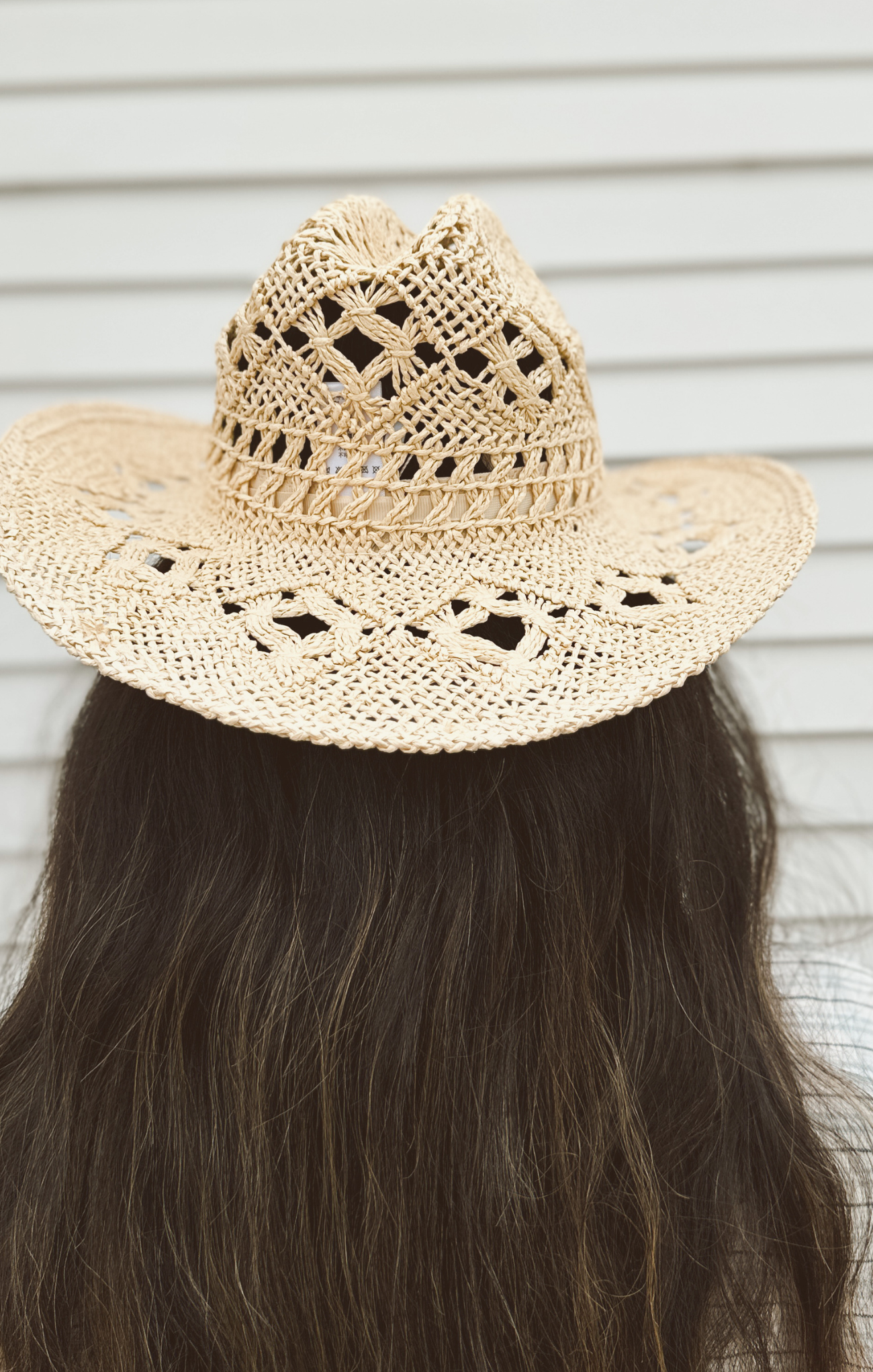 Beige straw hat with intricate patterns on a neutral background