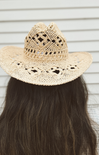 Beige straw hat with intricate patterns on a neutral background