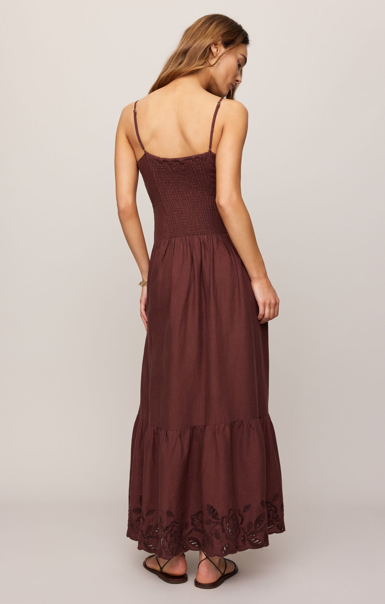 Woman wearing a brown dress with thin straps on a plain background