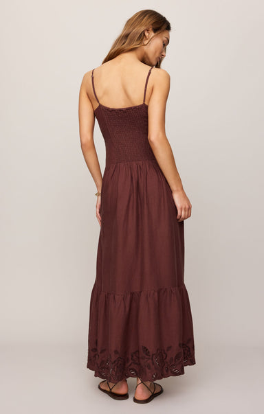 Woman wearing a brown dress with thin straps on a plain background