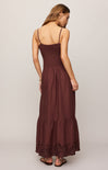 Woman wearing a brown dress with thin straps on a plain background