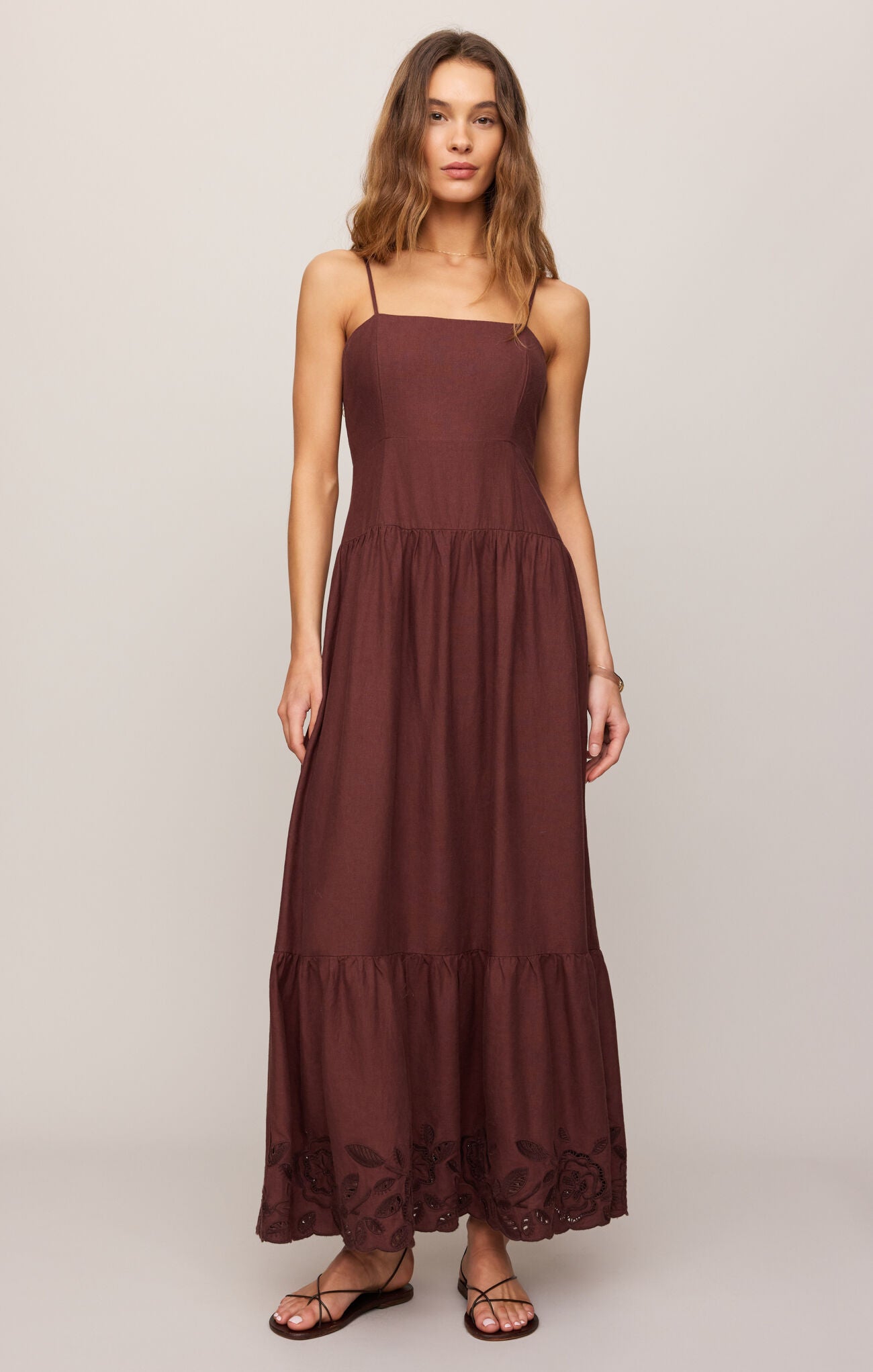 Woman wearing a brown maxi dress on a plain background