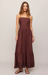 Woman wearing a brown maxi dress on a plain background