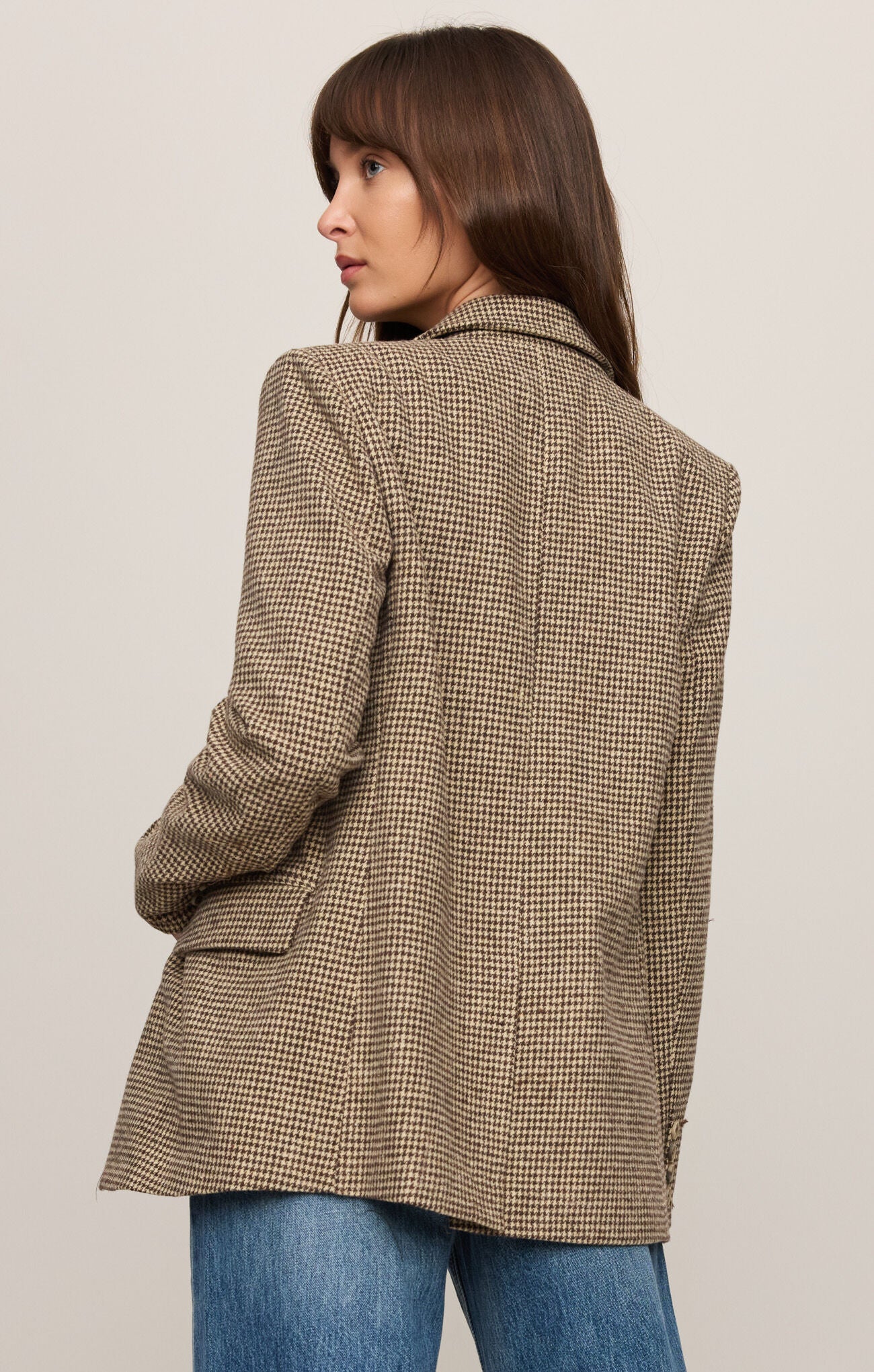 Woman wearing a brown checkered coat against a plain background
