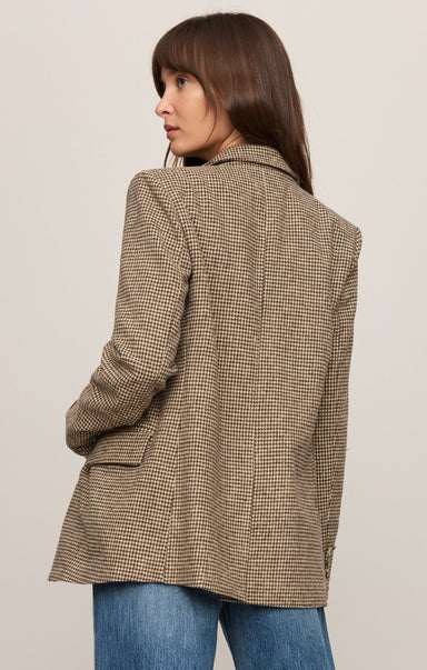 Woman wearing a brown checkered coat against a plain background